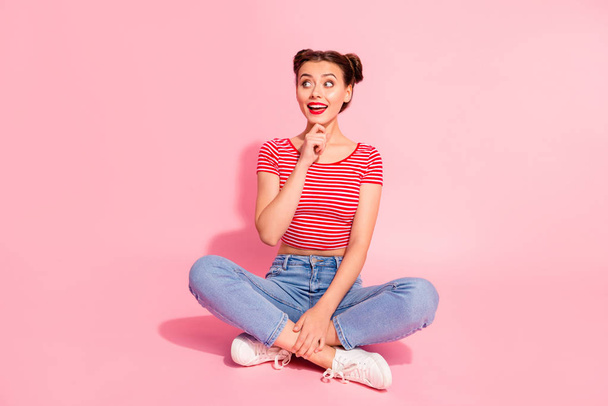 Full length body size photo beautiful she her lady buns pomade lips hold hand arm chin look empty space wondered wear casual jeans denim striped red white t-shirt sit floor isolated pink background - Photo, Image