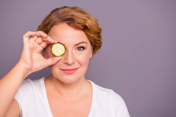 Close up photo beautiful amazing mature she her lady spa procedures hold cucumber slice hide eye nature treatment ideal condition under eyes bags wear white t-shirt isolated grey background - Foto, afbeelding