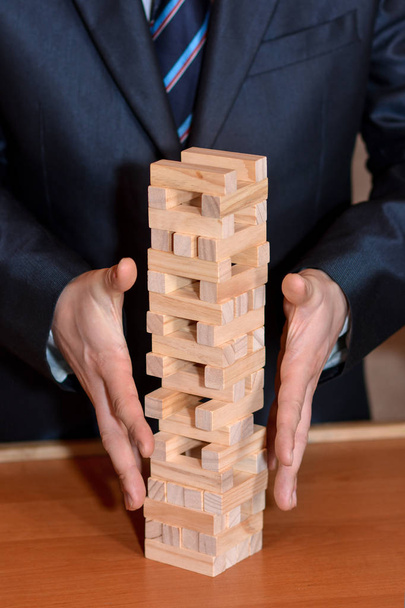 Pojęcie ryzyka alternatywnych, planu i strategii w biznesie. Businessman's rękę stara się trzymać wieża drewniane klocki. - Zdjęcie, obraz