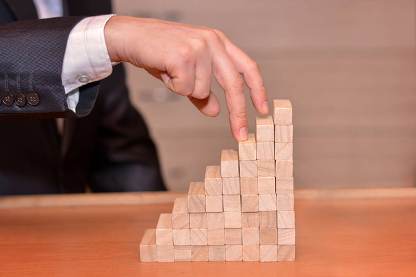 The hand of a businessman reached the goal of the wooden blocks - Photo, Image
