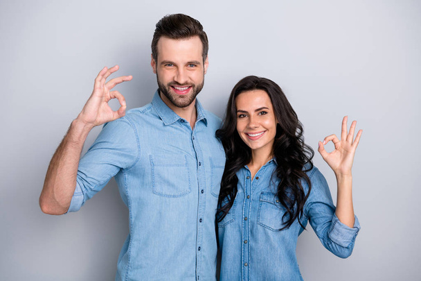 Close up portrait two amazing she her he him his couple lady guy couple stand close hold hands arms show okey symbol wear casual jeans denim shirts outfit clothes isolated light grey background - Zdjęcie, obraz