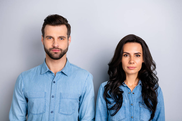 Close up portrait of two attractive fellows colleagues thinking about work problems questions listening attentively isolated in blue denim shirts over argent background - Foto, afbeelding