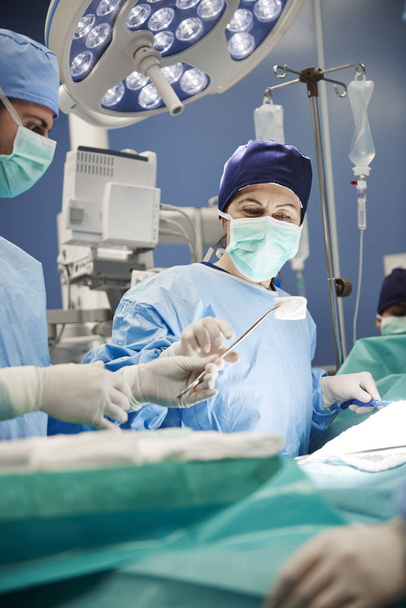 Chirurghi che si passano le forbici durante un'operazione
  - Foto, immagini