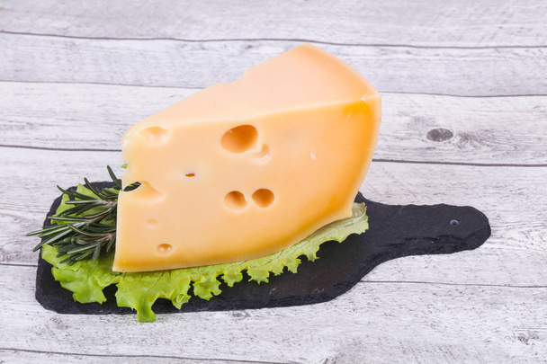 Маасдамский сыр в доске подают листья салата
 - Фото, изображение