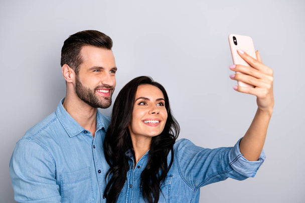 Close up photo couple she her he him his lady guy telephone smart phone hands arms make take selfies speak tell skype wear casual jeans denim shirts outfit clothes isolated light grey background - Foto, Imagem