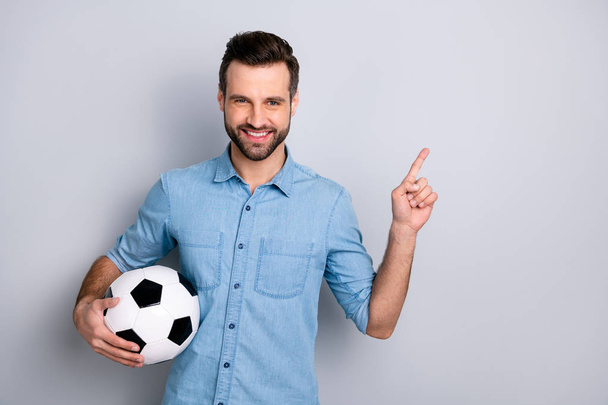 Close up photo macho he him his guy show hand arm finger empty space hold football leather ball watch match game fan advise wear casual jeans denim shirts outfit clothes isolated light grey background - Fotografie, Obrázek