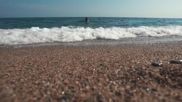 Zeegezicht in de zomer dag, uitzicht vanaf de grond van kiezelstrand, de mens is zwemmen - Video