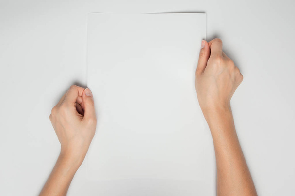 Μια γυναικεία χέρια κατέχουν μια κενή Λευκή Βίβλο απομονωμένη σε λευκό φόντο - Φωτογραφία, εικόνα