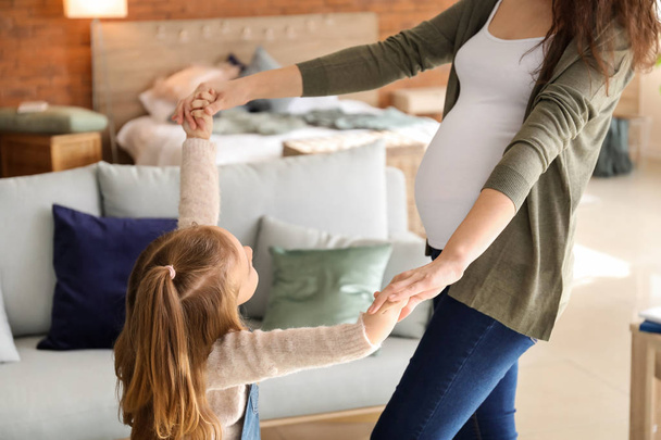 Embarazada madre con pequeña hija bailando en casa
 - Foto, imagen