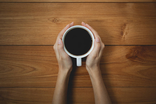 woman hands holding mug of hot drink that standing on wooden table - Φωτογραφία, εικόνα