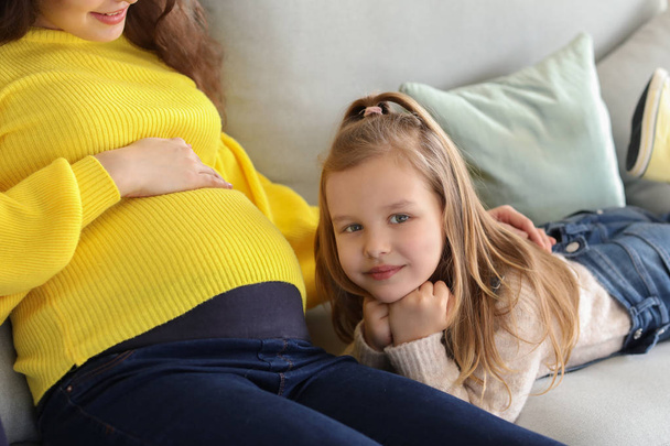 Little girl with pregnant mother at home - Foto, Imagen