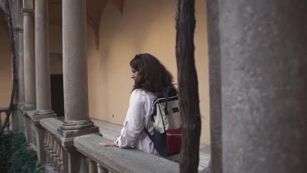 Traveler woman is admiring ancient building of palace, walking on stone balcony - Footage, Video