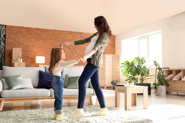 Pregnant mother with little daughter dancing at home - Photo, Image