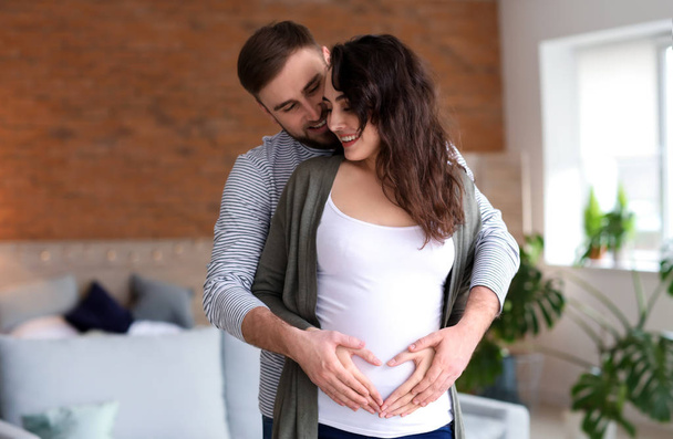 Portrait of happy pregnant couple at home - Photo, Image