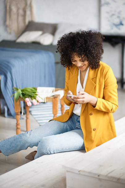 Lifestyle Concept - Portrait of beautiful African American woman joyful listening to music on mobile phone. Yellow pastel studio background. Copy Space. - Foto, Bild