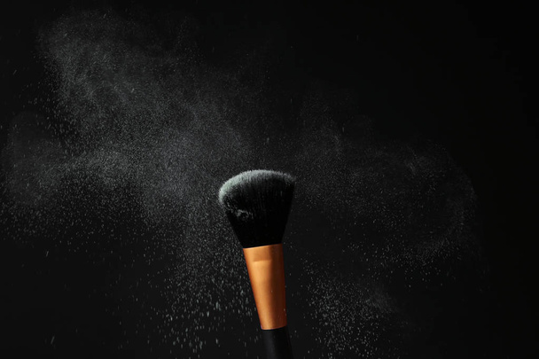 Brosse de maquillage avec explosion de poudre sur fond noir
 - Photo, image