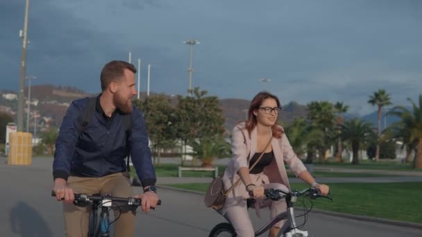 Young man and woman are meeting and riding bikes in park in daytime - Imágenes, Vídeo