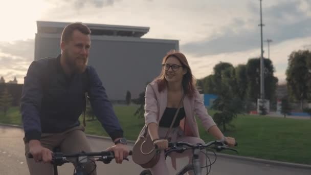 Young man and his girlfriend are riding bikes in a city in summer evening - Imágenes, Vídeo