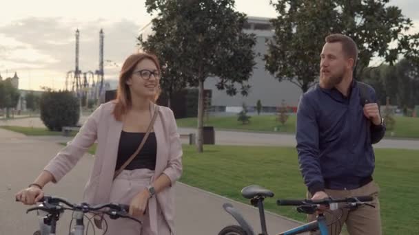 Happy lovers are walking together in park, rolling their bikes near - Imágenes, Vídeo