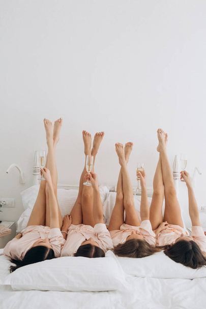 bachelorette party bed lying legs champagne glasses - Foto, imagen