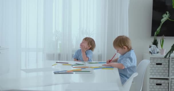 Deux frères garçons s'assoient à une table dans le salon et dessinent avec des crayons sur papier. Maman se lève et étreint les garçons, souriant et caressant sa tête. Louange et aide à faire la tâche
 - Séquence, vidéo