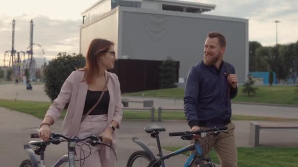 Man and woman talking on a walk rolling bicycles. - Video