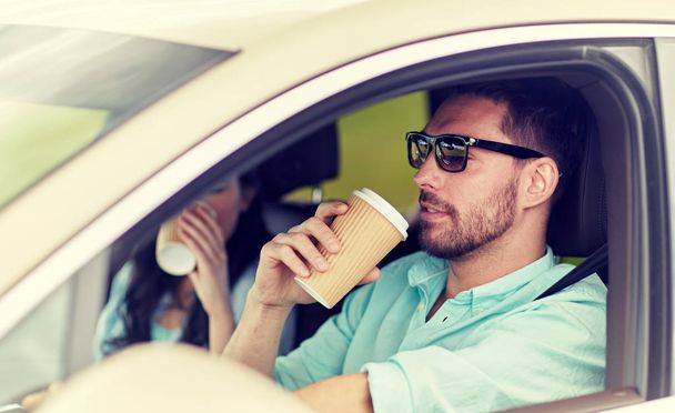 happy man and woman driving in car with coffee - Fotografie, Obrázek