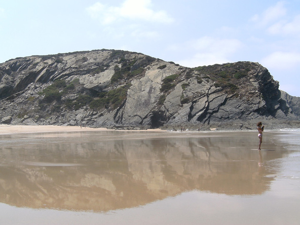eine Frau und ein Spiegelbild der riesigen Felsen im Meer - Foto, Bild