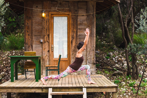 Una mujer practica yoga en el porche de una antigua casa de madera
. - Foto, imagen