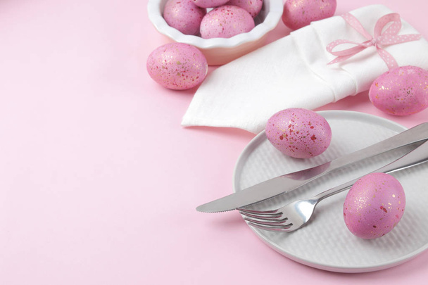 Великдень. Рожеві великодні яйця і тарілка, ніж і виделка на модному рожевому тлі. Пасхальний стіл. Щасливого Великодня. канікули
. - Фото, зображення