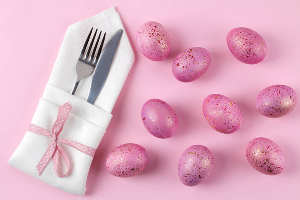 Semana Santa. Huevos de Pascua rosados y plato, cuchillo y tenedor sobre un fondo rosa de moda. Mesa de Pascua. Feliz Pascua. vacaciones. vista superior
 - Foto, imagen