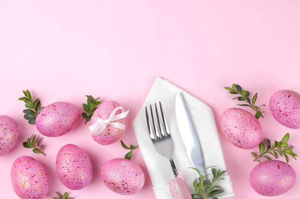 Pasen. Roze paaseieren en plaat, mes en vork op een trendy roze achtergrond. De instelling van de tabel van de Pasen. Vrolijk Pasen. vakantie. bovenaanzicht - Foto, afbeelding