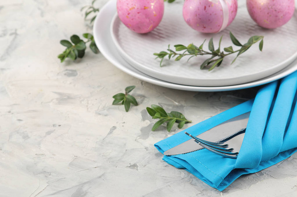 Pasen. Roze Easter eggs en een mes met een vork en een plaat op een lichte concrete achtergrond. De instelling van de tabel van de Pasen. Vrolijk Pasen. vakantie. - Foto, afbeelding