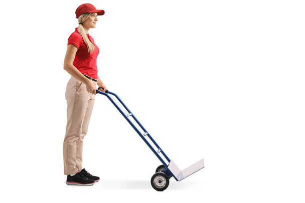 Full length shot of a female worker standing with an empty hand truck isolated on white background - Photo, image