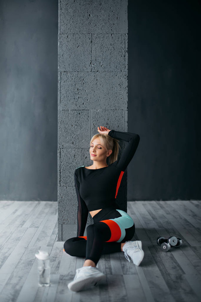 athletic woman sitting on floor in gym - Photo, image