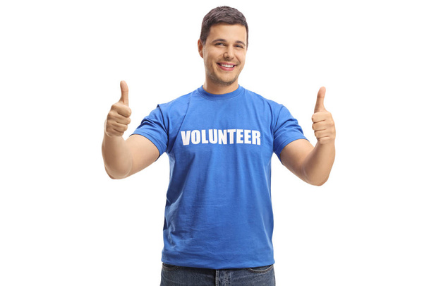 Young man volunteer in a blue t-shirt giving thumbs up isolated on white background - Fotografie, Obrázek