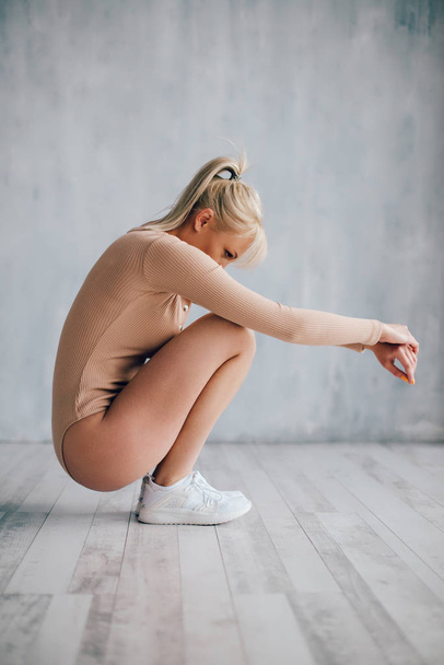 woman in knitted body squats on floor - Fotó, kép