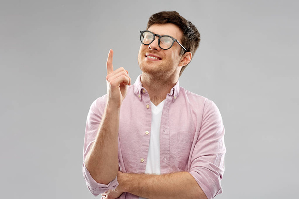 smiling young man in glasses pointing finger up - Fotografie, Obrázek