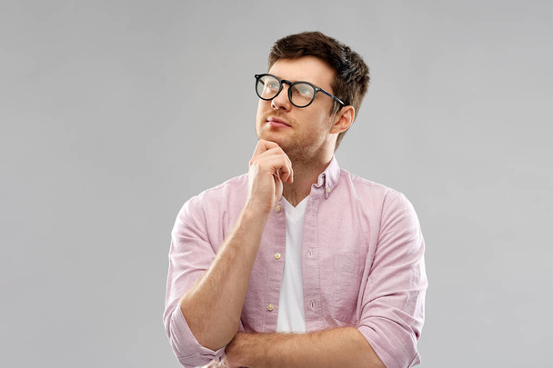 thinking young man in glasses over grey background - Φωτογραφία, εικόνα