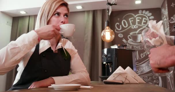 Vrouwelijke serveerster drinkt koffie en maakt gebruik van een papieren servet - Video