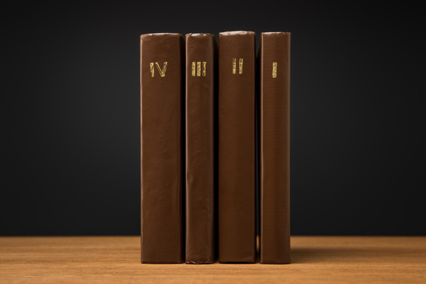 volumi di libri antichi in pelle marrone copertine su tavolo in legno isolato su nero
 - Foto, immagini