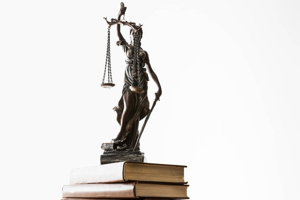 бронзовая статуэтка с весами правосудия на груде коричневых книг, изолированных на белом
 - Фото, изображение