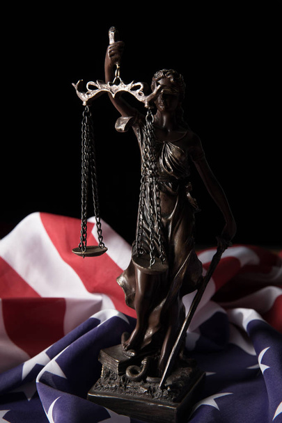 Bronzestatuette mit Maßstäben der Gerechtigkeit und amerikanischer Flagge isoliert auf schwarz - Foto, Bild