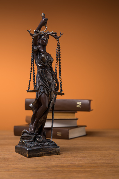 Adalet ve ahşap masa üzerinde kahverengi kitap birimlerin bronz heykelciği ile seçici odak ölçekler - Fotoğraf, Görsel