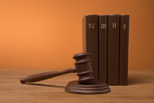 selective focus of volumes of brown books in leather covers and gavel on wooden table  - Photo, Image