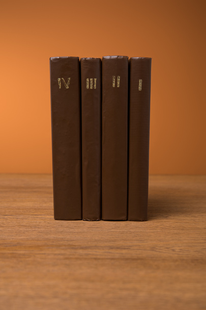 volumes of old books in leather brown covers on wooden table  - Photo, Image