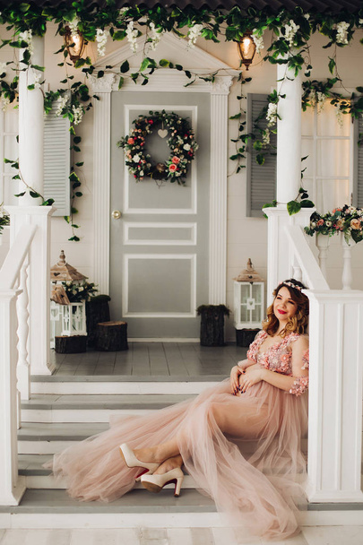Pregnant woman sitting on big decorated vine wreath. - Photo, image