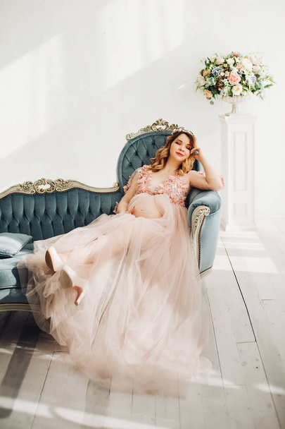 Těhotná žena sedí na velké zdobené révy věnec. - Fotografie, Obrázek
