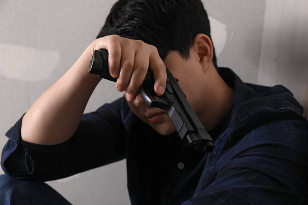 Молодой человек с пистолетом собирается покончить с собой дома
 - Фото, изображение