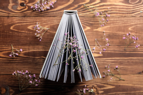 Book with flowers on wooden background - 写真・画像